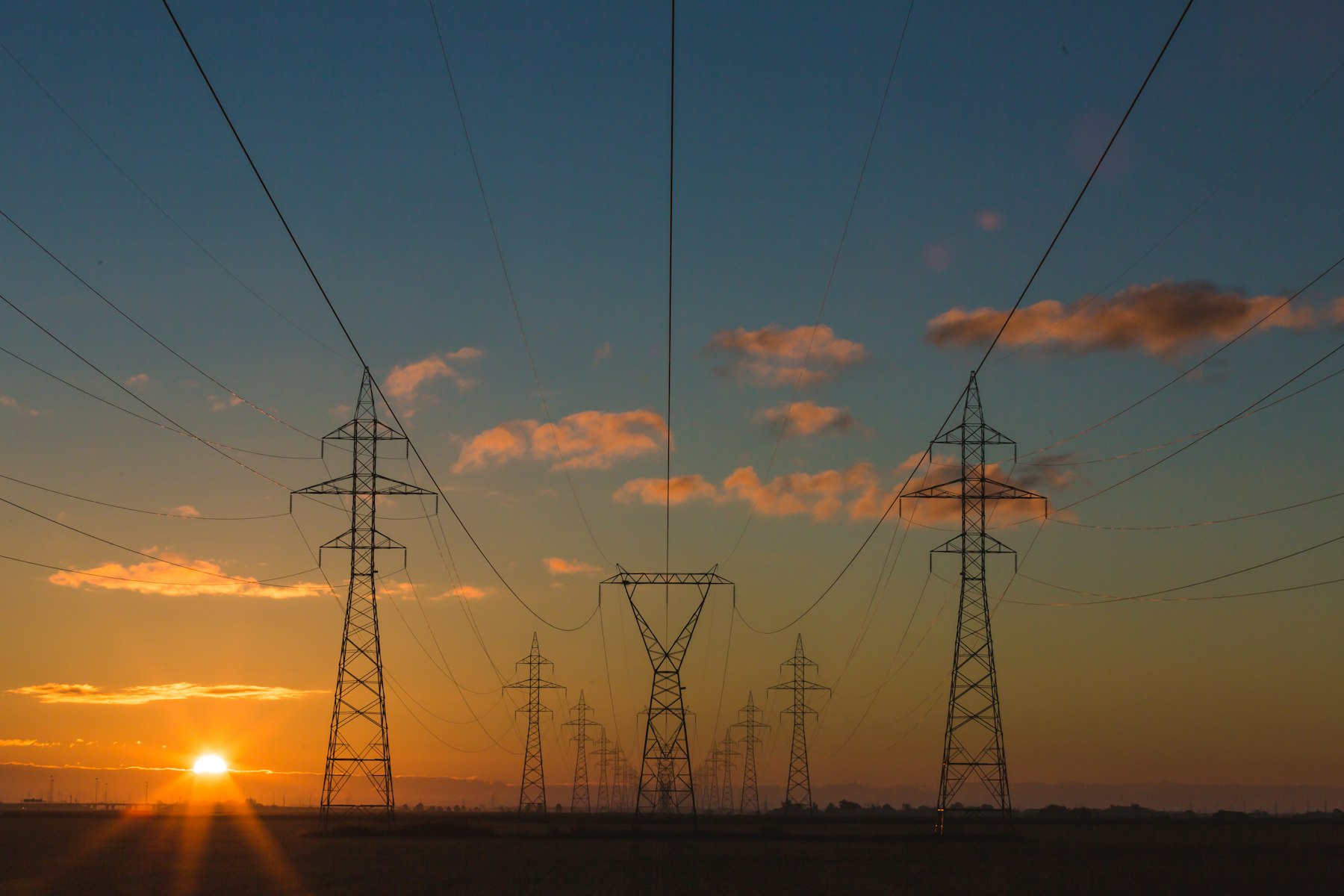 Electricity transmission towers against a sunset sky